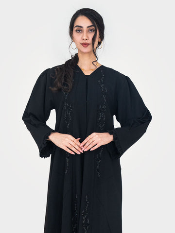 Noir Ruffle Abaya full length front view in black twill crepe with puff shoulders tonal bead sequin embellishment and ruffle cuffs UAE
